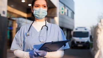 healthcare worker wearing mask standing in front of hospital